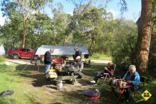 A happy group of campers preparing and tucking into a hearty bush breakfast.